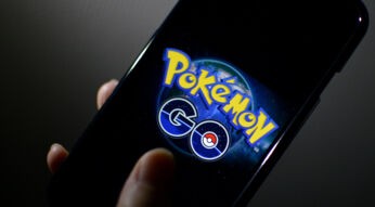 Eine Hand hält ein Smartphone, auf dem das "Pokémon GO"-Logo zu sehen ist.