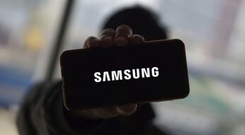 Mann hält Smartphone hoch, auf dem das Samsung-Logo zu sehen ist.