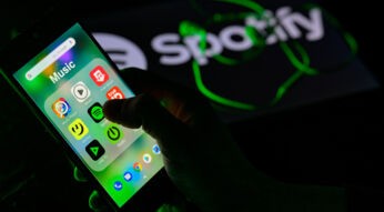 Hand tippt auf das App-Symbol für Spotify auf einem Handy.