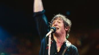 In Springsteen: Deliver Me From Nowhere steht Jeremy Allen White als Bruce Springsteen auf der Bühne, die rechte Faust triumphierend in die Luft gestreckt.