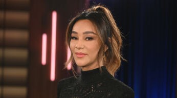 Dieses Symbolbild zu Villa der Versuchung 2026 zeigt Moderatorin Verona Pooth in einem schwarzen, hochgeschlossenen Oberteil mit feinem Muster. Sie steht vor einem Studiolicht-Hintergrund mit dunklen Blau- und Rosatönen. Ihr Blick ist ruhig und selbstbewusst, das Bild vermittelt eine elegante und professionelle Stimmung.