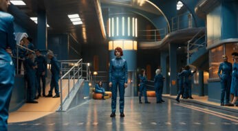 Asia (Alicia Falcó) steht im Bunker, im Hintergrund weitere Bewohner.