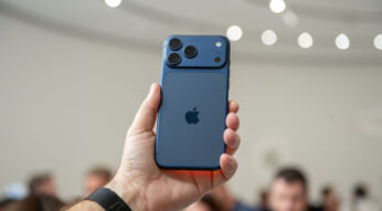 Hand hält das iPhone 17 Pro in Blau in die Höhe, im Hintergrund sind unscharf Menschen zu erkennen