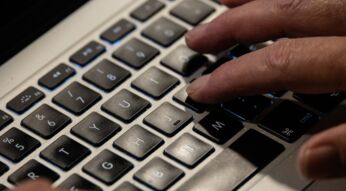 Jemand tippt mit seinen Fingern auf der Tastatur eines MacBooks.