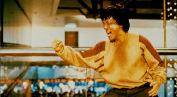 Das Bild zeigt Jackie Chan in einer ikonischen Szene aus Police Story. Schweißgebadet und voller Energie schreit er kampfbereit mit geballter Faust – typisch für seine Rolle als einer der kompromisslosesten Actionhelden der 80er und 90er. Der Hintergrund zeigt ein Einkaufszentrum, in dem gerade eine intensive Actionszene stattfindet.