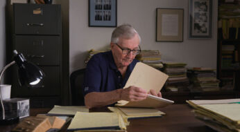 Seymour Hersh sitzt an einem Schreibtisch und blättert durch seine Unterlagen.