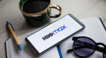 Ein Smartphone mit dem HBO-Max-Schriftzuf auf dem Display liegt auf einem Tisch.