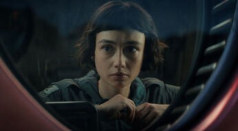 In den besten Serien 2025 siehst du eine Szene aus Alien: Earth. Sydney Chandler als Wendy blickt ernst und konzentriert durch ein rundes Fenster mit technischer Umrahmung.