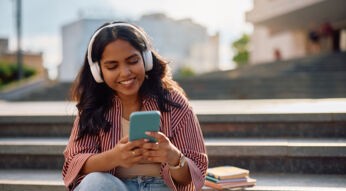 Auf dem Bild in dem Artikel zu den besten Hörbüchern 2025 laut BookBeat ist eine junge Frau mit langen dunklen Haaren mit Kopfhörern zu sehen.