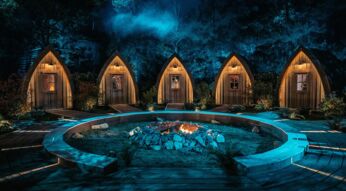 Auf dem Bild in dem Artikel zu „Werwölfe“ Staffel 2 ist ein nächtliches Set mit fünf kleinen, beleuchteten Holzhütten zu sehen.