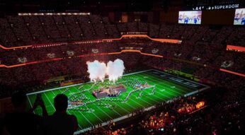 Auf dem Bild in den GigaTV-Highlights im Februar 2026 siehst Du eine Szene vom Super Bowl. In einem riesigen Stadion sind tausende Zuschauer zu sehen, während auf dem Spielfeld eine spektakuläre Halbzeitshow mit Rauch, Licht und Choreografien stattfindet. Die Stimmung wirkt energiegeladen, monumental und voller sportlicher und musikalischer Highlights.