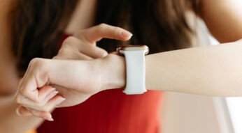 Auf dem Bild zum Keyword Smartwatch ohne Handy ist eine Person zu sehen, die eine moderne Smartwatch mit hellem Armband am Handgelenk trägt. Mit dem Zeigefinger der anderen Hand bedient sie den Bildschirm. Der Hintergrund ist weich unscharf, die Szene wirkt ruhig, alltagsnah und fokussiert auf die Nutzung der Uhr.