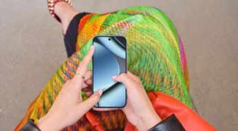 Eine sitzende Frau schaut nach unten auf das Pixel 10 Pro in ihrer Hand.