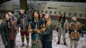 Auf dem Bild zu den Serien-Neustarts neu auf Paramount+ steht die Gruppe junger Überlebender aus „Yellowjackets” Staffel 4 im Schnee vor dem Rumpf ihres abgestürzten Flugzeugs. In abgenutzter, zusammengeflickter Winterkleidung blicken alle angespannt nach oben, einige klammern sich aneinander. Der verschneite Wald und das fahle Licht verstärken die bedrohliche, erschöpfte Stimmung der Szene.
