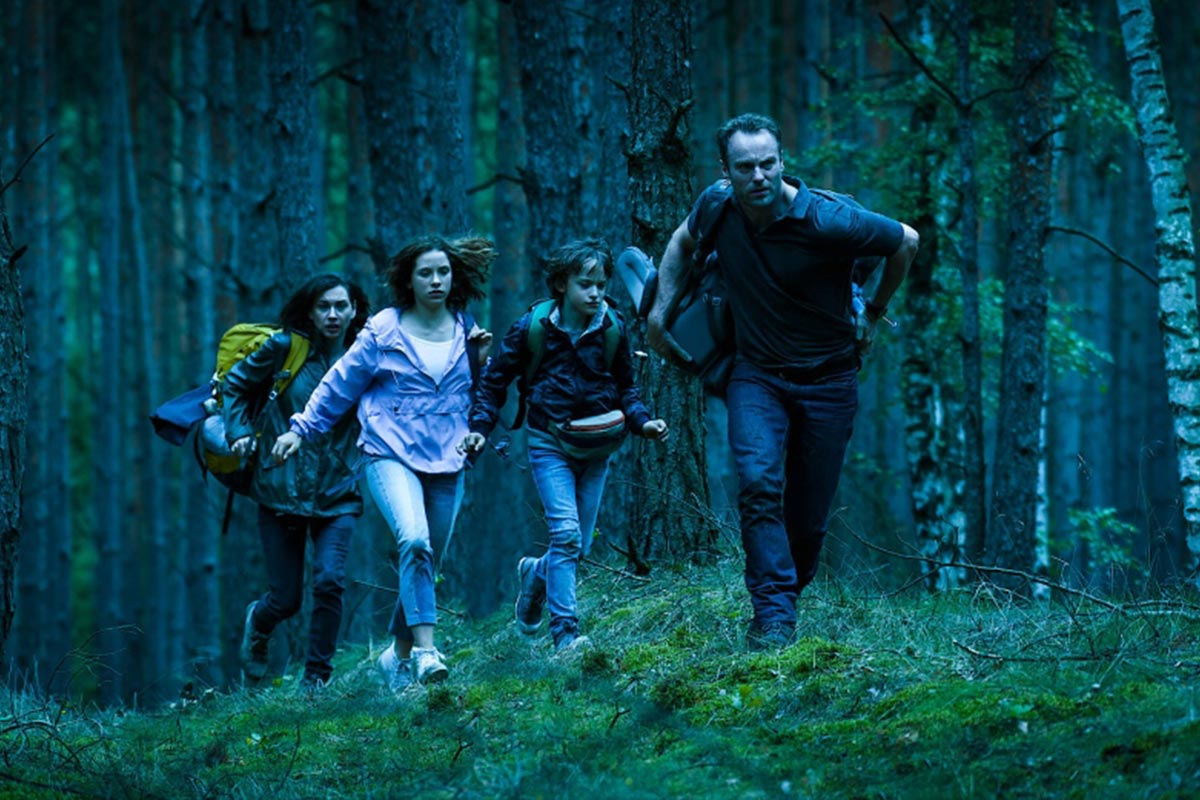 Das Bild zeigt eine Familie die durch den Wald läuft.