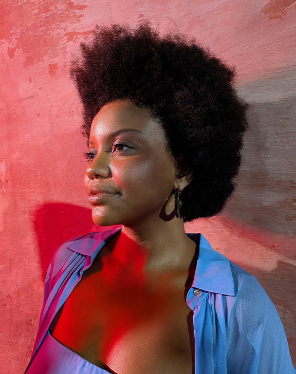 Lifestyle-Bild einer Frau vor einer Wand in roter Beleuchtung.