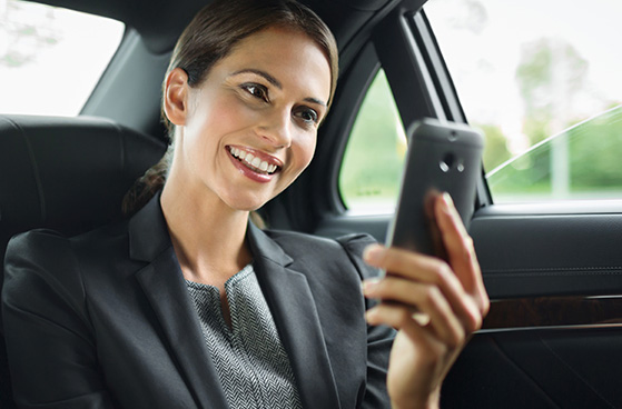 Business-Frau nutzt im Auto ihr Smartphone mit 4G|LTE in einem zuverlässigen Netz.