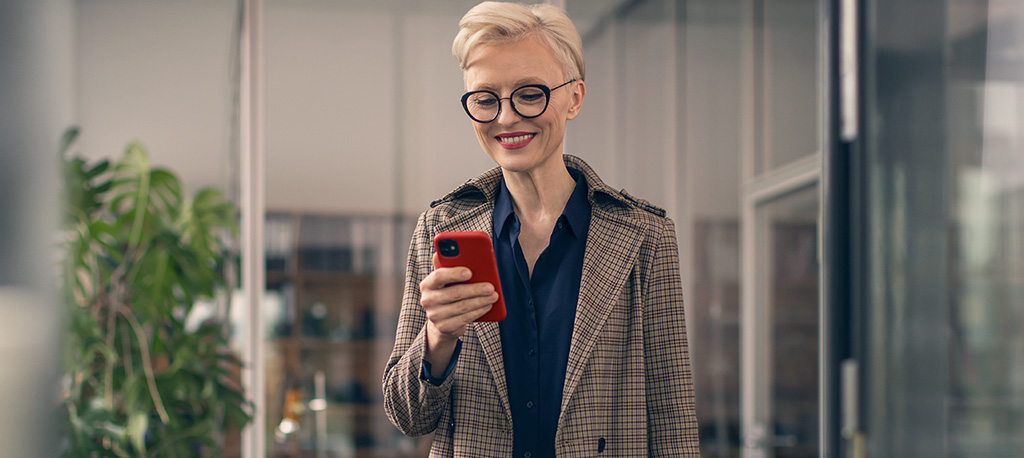 Frau mit Business-Smartphone bucht am Telefon ihre OneNumber oder eSIM