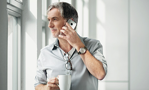 Ein Mann telefoniert mit Kaffeetasse in der Hand.