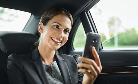 Business-Frau im Auto schreibt eine SMS.
