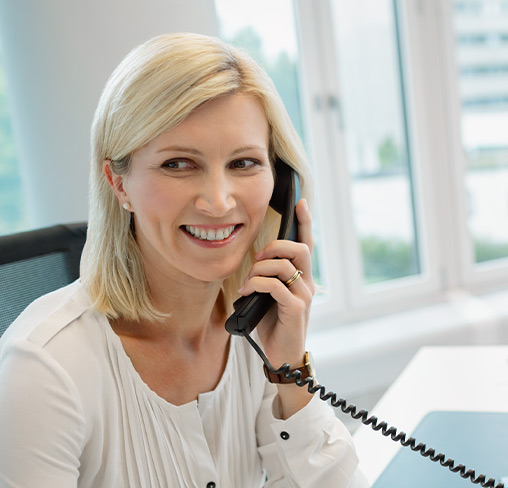 Frau telefoniert am Schreibtisch mit einer Cloud-Telefonanlage 