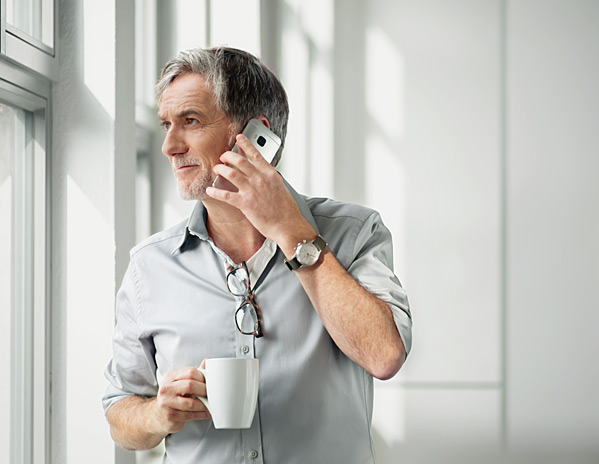 Ein Mann mit Tasse in der Hand telefoniert über WiFi Calling von Vodafone.