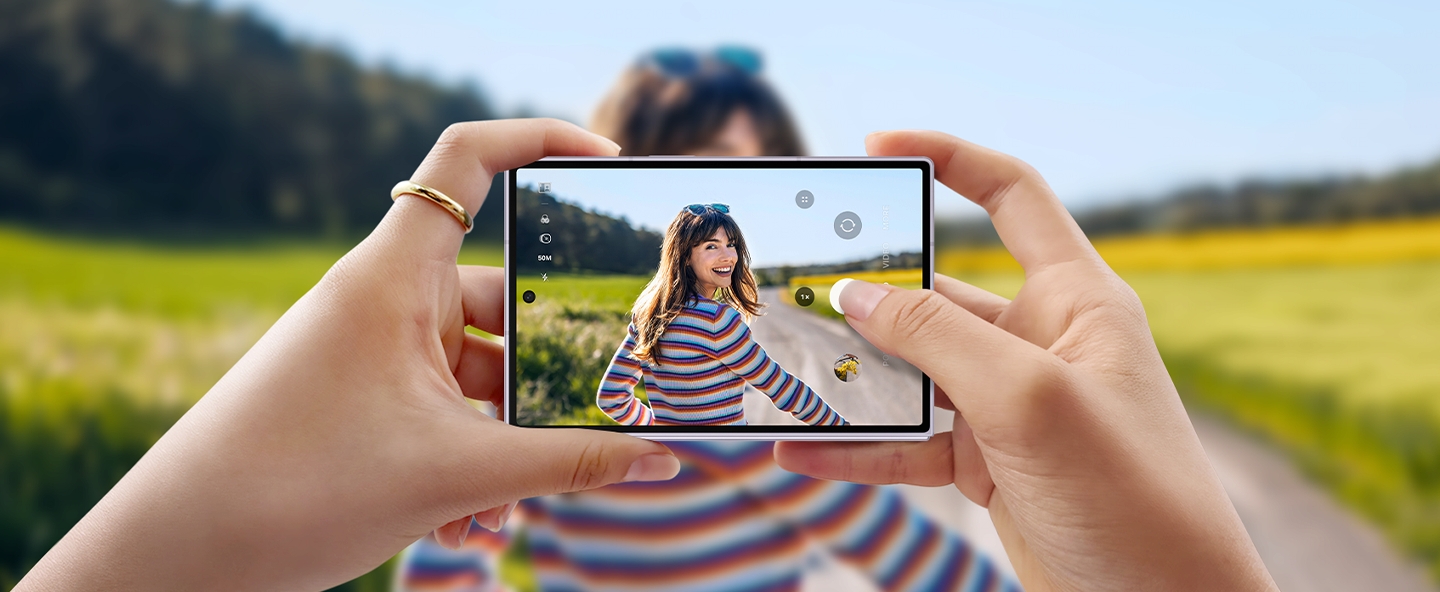 Mit einem Galaxy Z Fold8 wird eine Person vor einer malerischen Kulisse fotografiert. Das Ger�t wird zusammengeklappt und horizontal gehalten. Das Foto ist auf dem Frontdisplay zu sehen.